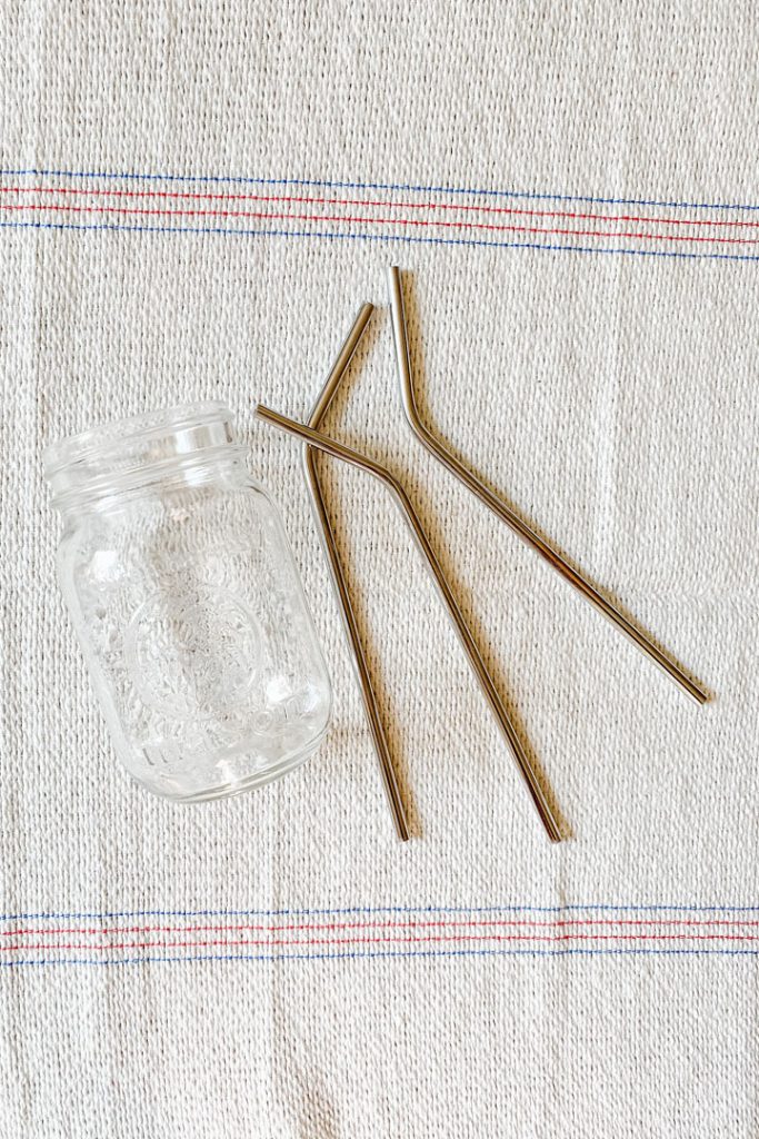 one glass jar lying beside 3 stainless steel straws 